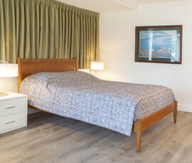 Seal Rock Inn - Room 104 - Bed and bedside table.